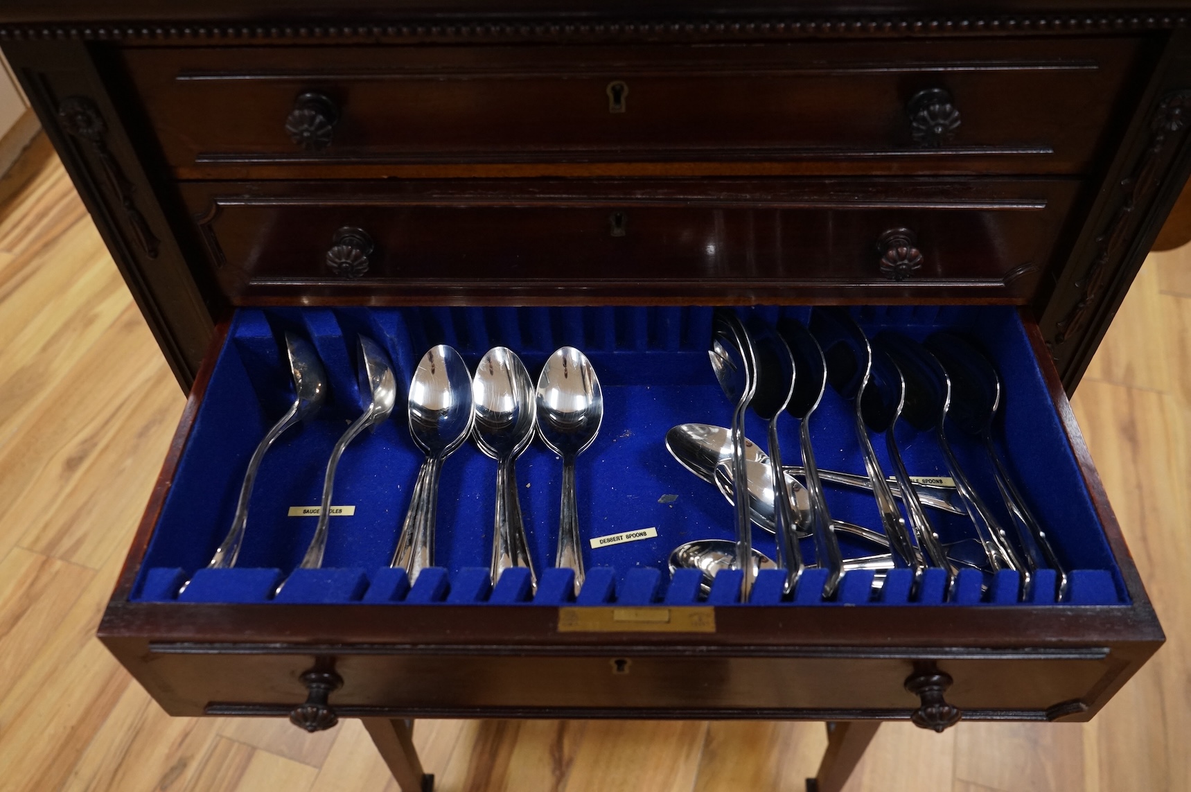 A canteen of cutlery by Viners, contained within a four drawer floor standing cabinet. 110cm tall